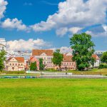 Traeckaje Suburb with old buildings in Trinity Hill district and grass lawn with green trees in Minsk city Nemiga historical centre, blue sky white clouds in sunny summer day, Republic of Belarus